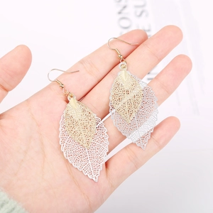 Detail of layered gold and silver leaf earrings with intricate hollow-out metal patterns