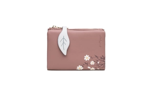 Close-up of pink faux leather wallet featuring a white leaf zipper pull and floral print