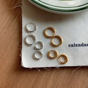 Three sizes of gold and silver minimalist 925 silver hoop earrings on a textured canvas