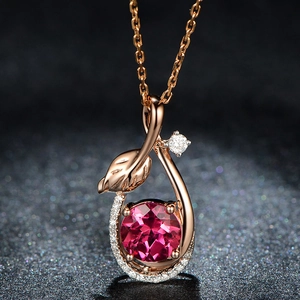 Macro detail of a rose gold leaf pendant set with a ruby and sparkling zircons