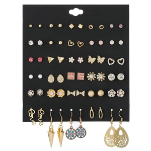 Macro shot of 30 pairs golden alloy stud earrings with crystals and pearls on black card