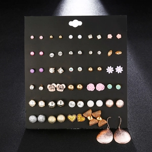 Detailed assortment of 24 pairs of crystal and pearl stud earrings on a black display board