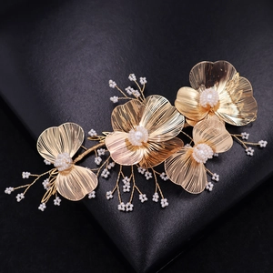 Detail of handmade gold floral hairpiece with woven wire petals and white pearls