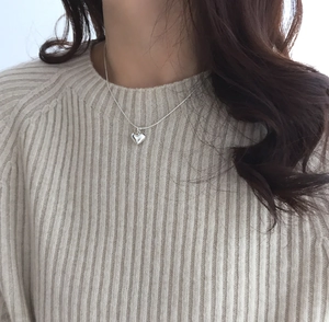 Model wearing a 925 sterling silver heart pendant necklace on an off-white knitted sweater