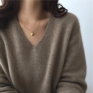 Close-up of golden heart pendant necklace on a model wearing a brown knit V-neck sweater