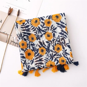 Detail of yellow floral cotton linen scarf with blue leaves and colorful tassels