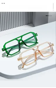 Detail of square glasses with double bridge design in emerald green and transparent apricot
