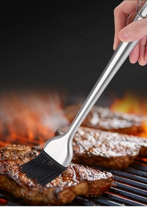 Detail of 304 stainless steel oil brush with a long handle applying oil to a grilled steak