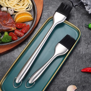 Set of two heat-resistant silicone basting brushes with stainless steel handles on a plate