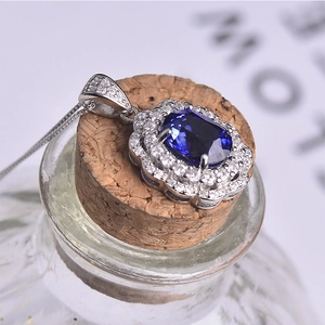 Detail of flower necklace pendant with oval blue crystal and paved diamonds