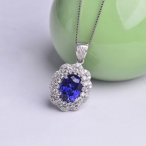 Detailed view of silver necklace with oval blue gemstone pendant and diamond double halo