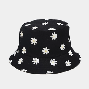 Detail of a black bucket hat featuring white daisy patterns and high-quality canvas fabric