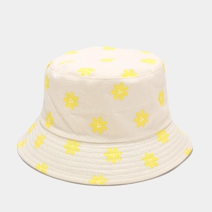 Close-up of a cream cotton bucket hat featuring vibrant yellow sunflower print patterns