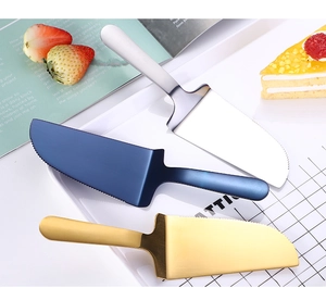 Three-color stainless steel cake servers in gold, blue, and silver on a dessert table