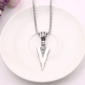 Close-up of silver arrowhead pendant on chunky chain placed on a ceramic plate