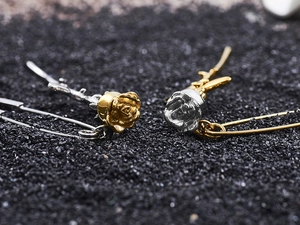 Macro shot of rose-shaped earrings featuring two-tone gold and silver metallic finish