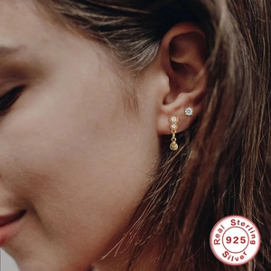 Close-up of S925 sterling silver gold-plated zircon stud earrings worn by a model