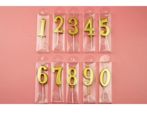 Flat lay of gold numeric birthday candles 0-9 in individual PVC boxes on pink background