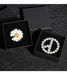 Détail de broches marguerite et signe de paix sur une boîte à bijoux en velours noir
