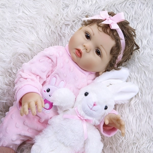 Gros plan d'une poupée réaliste de 47cm en barboteuse rose avec un lapin en peluche