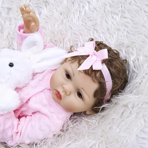 Détail d'une poupée réaliste de 47cm en tenue rose à pois avec son petit lapin blanc