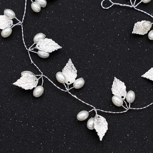 Silver bridal hair vine with metallic leaves and white pearls on a black background