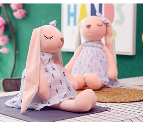 Close-up of pink long-eared plush rabbits wearing white patterned dresses in soft plush fabric