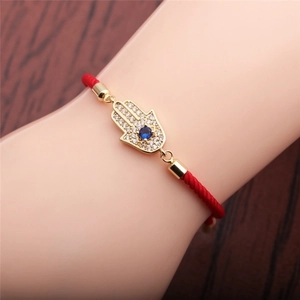 Rotes geflochtenes Armband mit goldenem Hamsa-Hand-Anhänger und blau-weißen Zirkonen