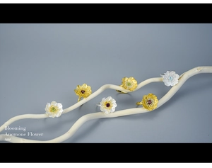 Artistic close-up of Blooming Anemone flower rings in gold and silver on white branches