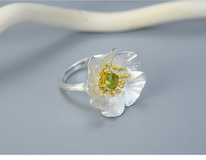 Macro detail of S925 silver flower ring featuring green gemstone and golden accents