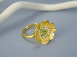 Macro shot of gold floral S925 silver ring featuring a vibrant green gemstone center