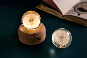 Detailed view of dandelion crystal ball with warm glowing light and natural wooden base