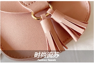 Detail view of pink leather bag featuring fashion tassels and golden metal ring hardware