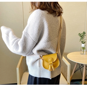 Close-up of yellow leather mini crossbody bag with tassel detail worn by child model