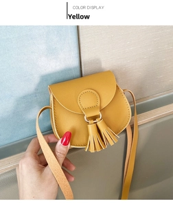 Detail view of yellow mini PU leather saddle bag with tassel and gold metal ring buckle