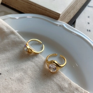 Detail of adjustable gold ring with oval zircon stones on a rustic fabric background