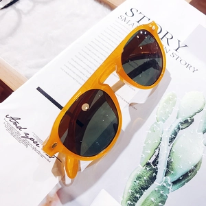 Detailed view of ginger orange acetate sunglasses with dark grey lenses on a magazine background