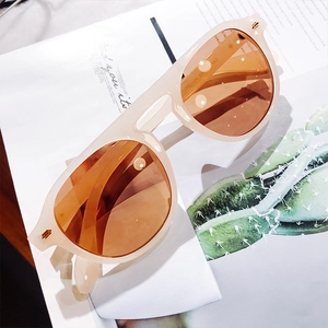 Detail of beige oversized sunglasses with amber lenses resting on a fashion magazine