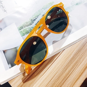 Detail of bright orange frame sunglasses with dark green lenses on a magazine