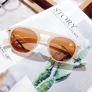Detailed view of cream acetate frame sunglasses with amber lenses and size engravings