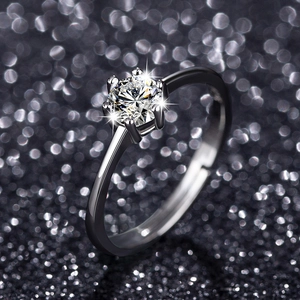 Macro shot of silver six-prong setting engagement ring with a round zircon on black background