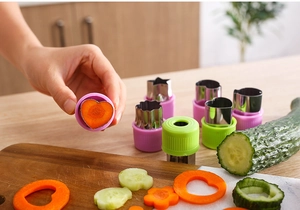 Macro view of stainless steel cutters slicing carrot and cucumber into flower shapes