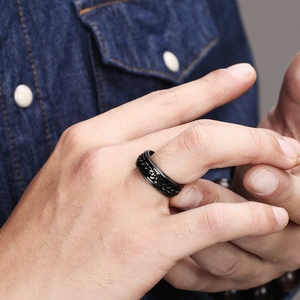 Close-up of black titanium rotating chain ring for men worn on finger over denim fabric