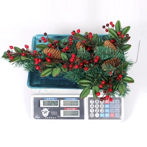 Weihnachtliche Hängedeko aus künstlichen Tannenzweigen mit roten Beeren und echten Tannenzapfen
