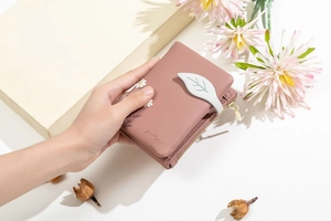 Close-up of pink women's wallet with daisy print and leaf magnetic clasp closure