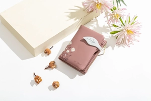 Close-up of pink faux leather wallet with daisy embroidery and leaf-shaped magnetic clasp