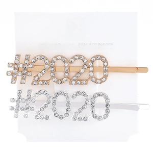 Close-up of gold and silver hair clips featuring #2020 sparkling rhinestone lettering