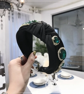 Detailed close-up of a vintage knotted headband with large emerald stones and crystals