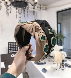 Detailed view of the knotted baroque headband with emerald gems and crystal embellishments