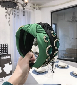 Detailed view of baroque knotted headbands with emerald green gemstones and crystal trim